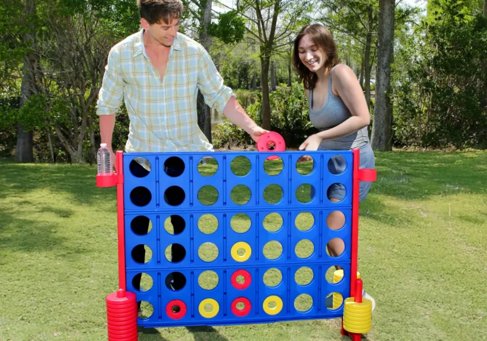 People playing giant Connect Four game outdoors.